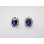 A pair of Sapphire and Diamond Cluster Earrings each claw-set oval-cut sapphire, approx 2cts, within