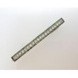 A French Art Deco Diamond and Emerald Brooch millegrain-set a row of rose-cut diamonds within a