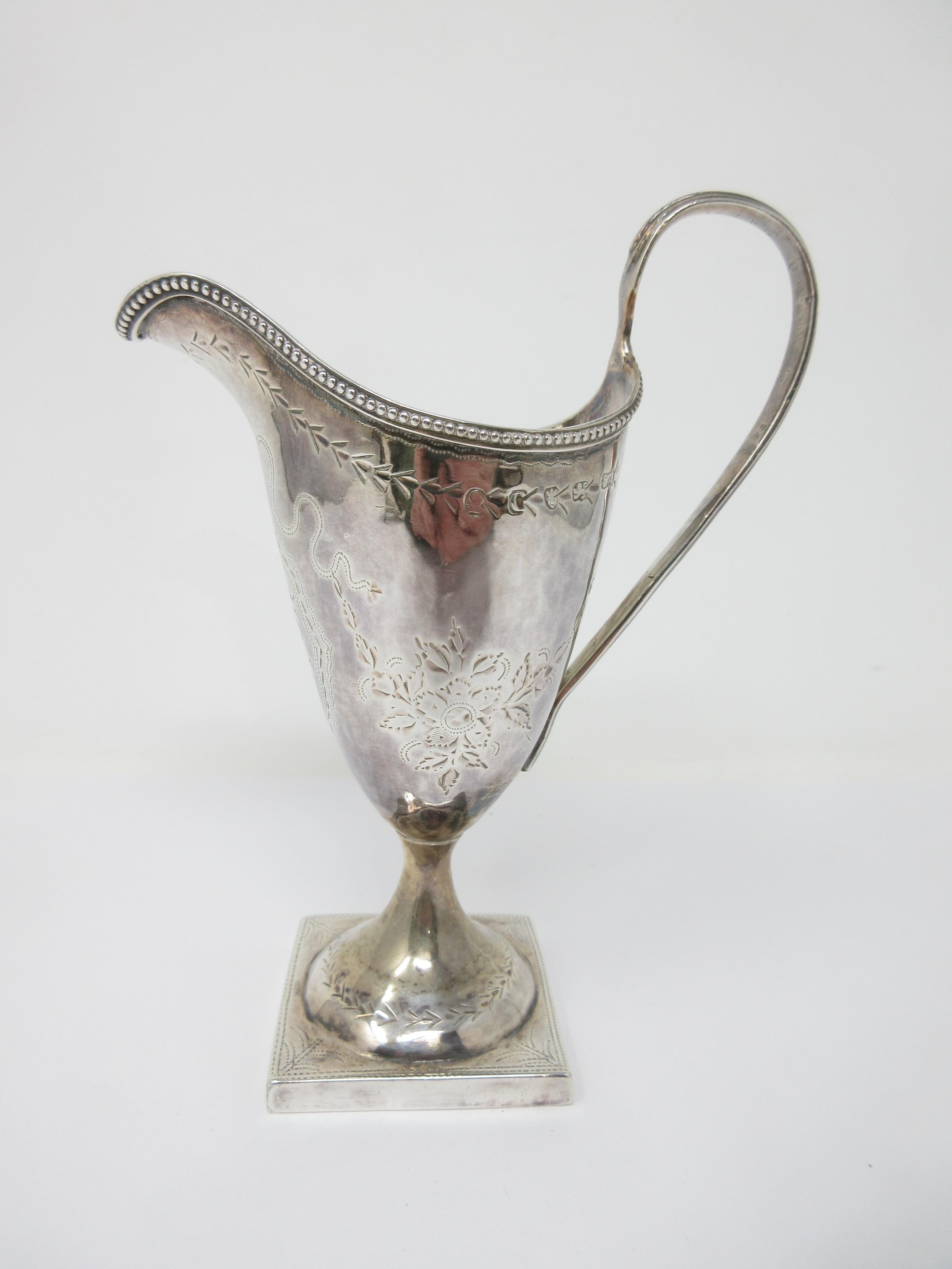 A George III silver helmet shape Cream Jug engraved floral swags, initials in cartouche, beaded
