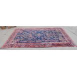 A large Persian style Carpet of multi-bordered design and decorated red sprays of flowers on a blue