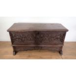 A 17th Century and later oak plank Chest with plain moulded lid above profusely carved front with fo