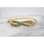 An Emerald and Diamond hinged Bangle the front with crossover design channel-set a row of calibré-cu