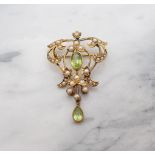 An Edwardian Peridot and Seed Pearl Pendant/Brooch millegrain-set oval-cut peridot within scrolled o