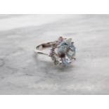 An Aquamarine and Diamond Cluster Ring claw-set oval-cut aquamarine, 4.70cts, within a starburst fra