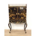 A black lacquered Cabinet on Stand with pierced brass surmount above a pair of doors decorated exoti