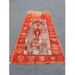 An Eastern Rug with wide border of stylised motifs, the central ground depicting figures, 12ft x 4ft
