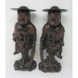 A pair of Oriental carved hardwood Figures of Chinamen wearing flowing robes and leafage carved cool