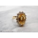 A Citrine and Diamond Cluster Ring claw-set oval-cut citrine, 3cts, within a frame of fourteen brill