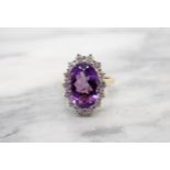 An Amethyst and Diamond Cluster Ring claw-set oval-cut amethyst, 3cts, within a frame of fourteen