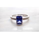 A Sapphire and Diamond Ring corner claw-set step-cut sapphire, 1.53cts, between pavé-set brilliant-