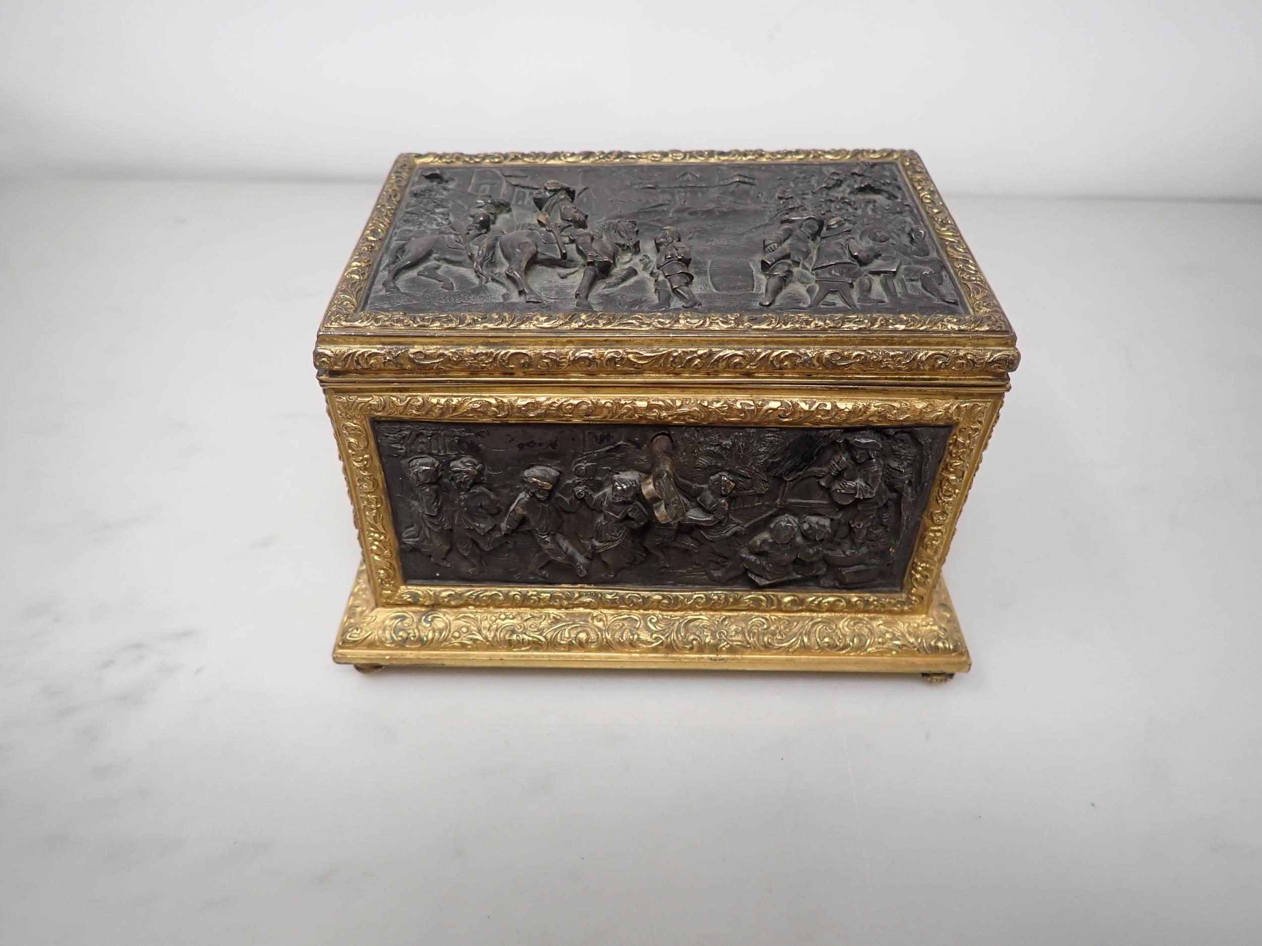 A 19th Century French gilt-metal and bronzed Casket, the inset panels decorated figures merrymaking,