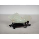 A Chinese celadon Jade carved Fish with lily pad and flower to one side, small chips, on hardwood