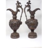 A pair of bronze pedestal Ewers in the classical style with cherub heads to the scroll handles and