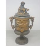 A cast metal Urn, partially gilt with cherub surmount to the cover and a frieze of cherubs in