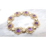 An Amethyst Bracelet comprised of eight openwork scrolled links each set oval-cut stone in 9ct gold,