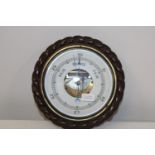 An antique barometer in an oak case with rope detailing 28cm in diameter