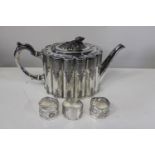 A antique silver plated tea pot and three napkin rings (one hallmarked silver)