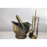 A vintage brass coal bucket and fireside tools
