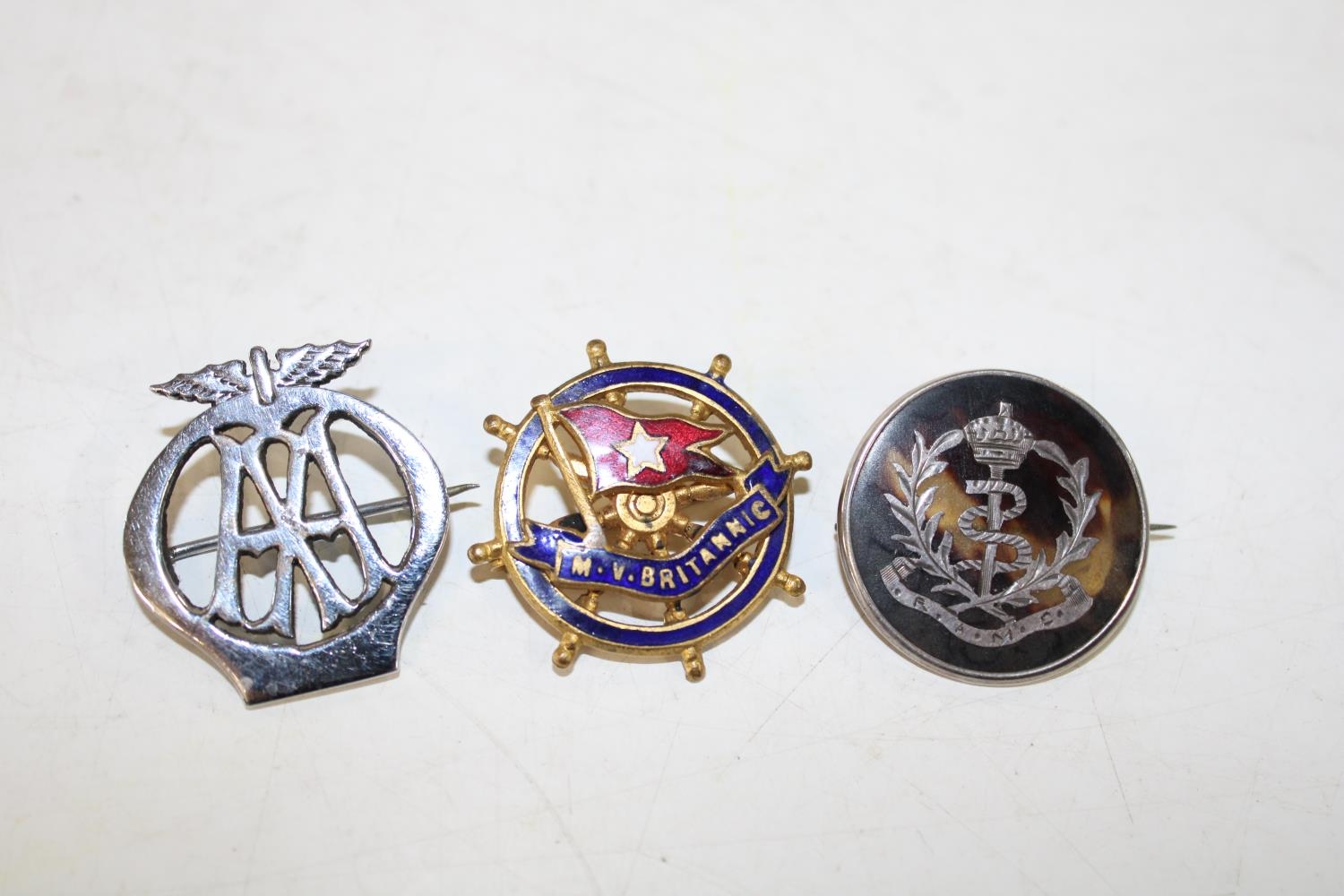 Three assorted collectable badges including silver