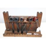 An antique oak pipe rack and six pipes