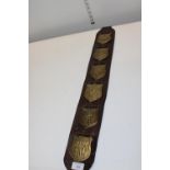 An unusual selection of horse brasses on a leather strap