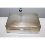 A silver cigarette box with engine turned decoration & monogram to the lid. Hallmarked for