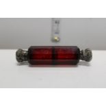 A double ended cranberry glass scent bottle with white metal fittings. At fault