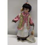 A bisque headed Oriental doll on stand