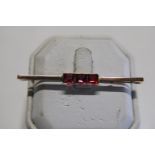 A 9ct gold bar brooch set with three pink stones