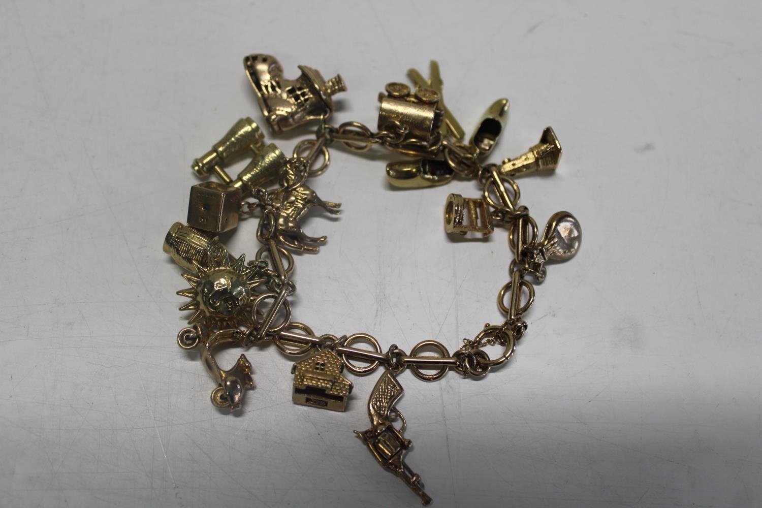 A 9ct gold charm bracelet with fifteen 9ct gold charms. 43.08 grams