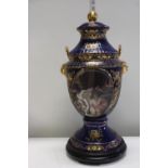 A large ceramic lidded urn on wooden base