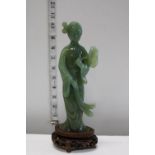 A jade figure on a wooden stand with slight damage to the figure
