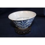 An antique Chinese blue and white bowl (has hairline crack ) on a carved wooden base