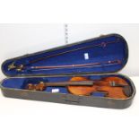 An antique Stradivarius copy violin in an early coffin carry case with bows (Sold as seen)
