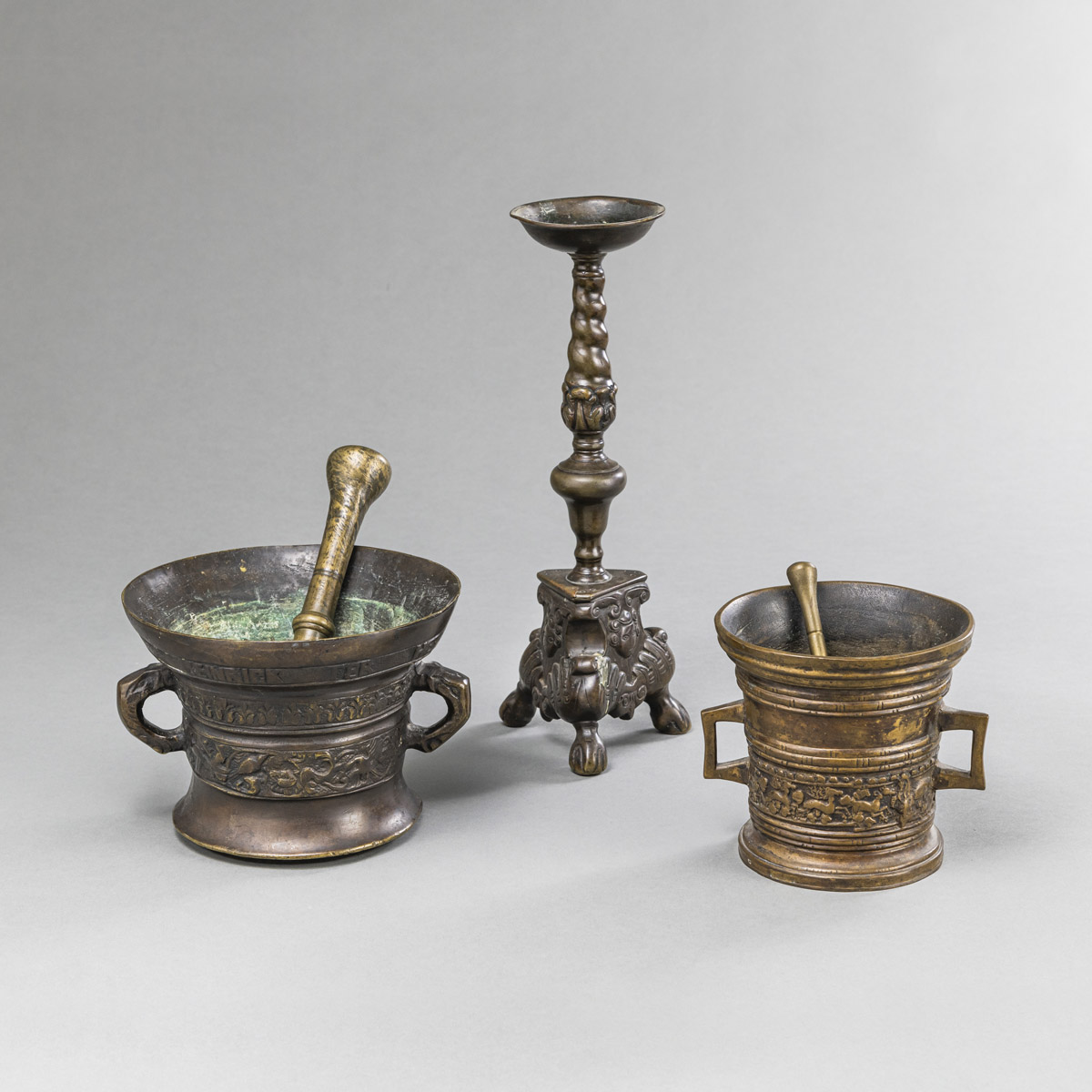 TWO BRONZE MORTARS WITH PESTLES AND A CANDLESTICK