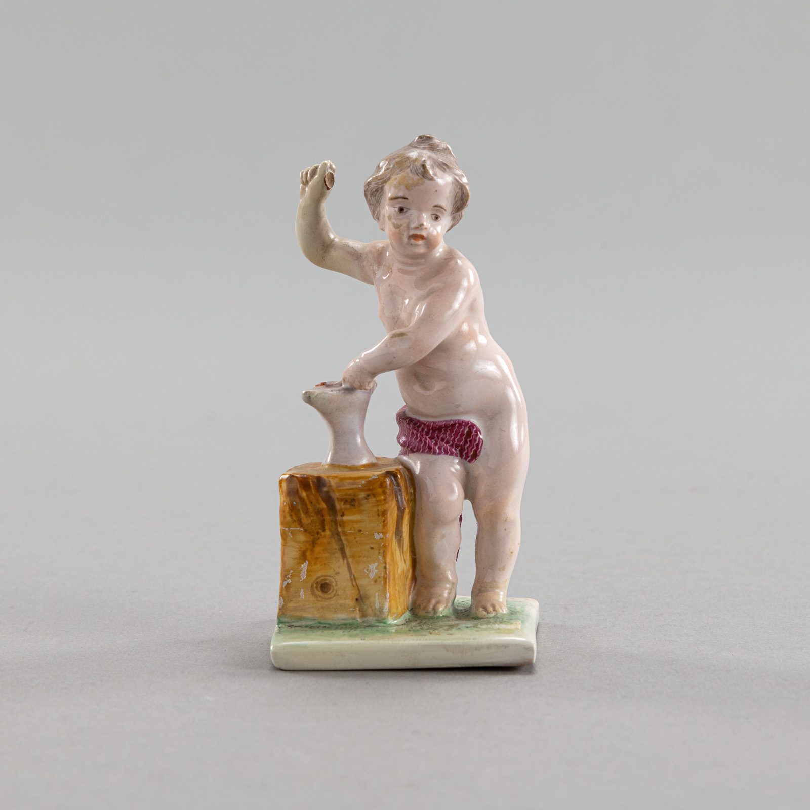 A CONTINENTAL FAYENCE FIGURE OF CUPID