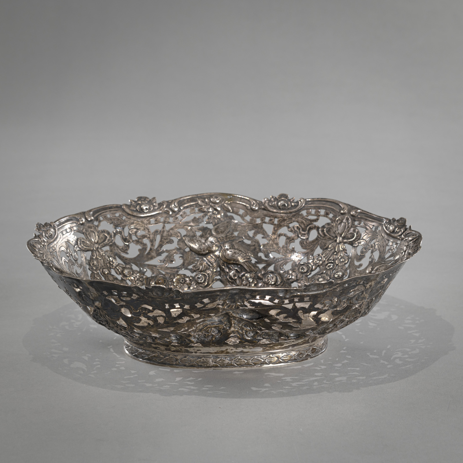 A GERMAN SILVER BASKET WITH PUTTI AND BIRD PATTERN