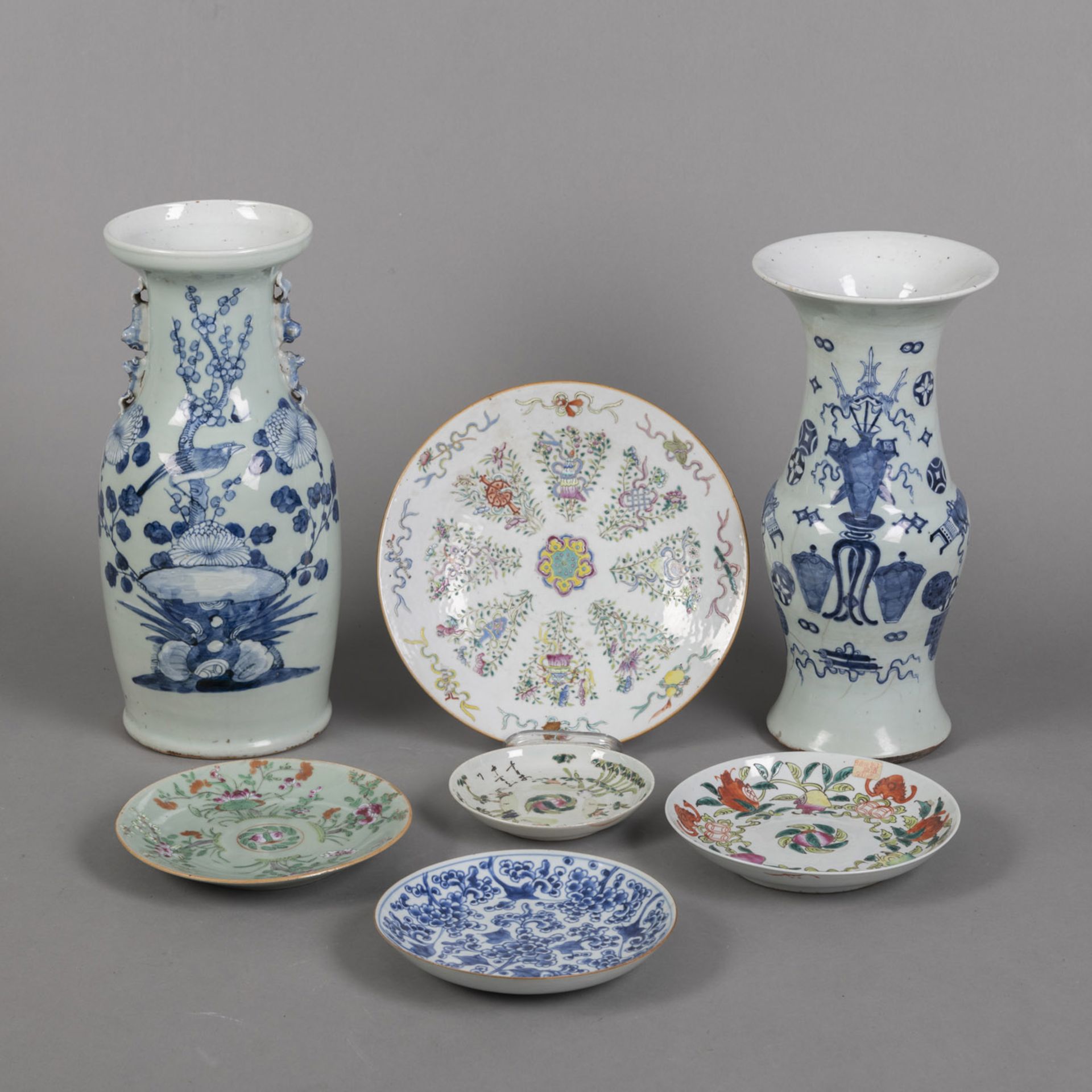 Fünf Teller und zwei Vasen aus Porzellan mit polychromem Schätzen- und Blumendekor