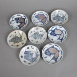 Acht Porzellanteller mit Fischdekor in Unterglasurblau und Kupferrot