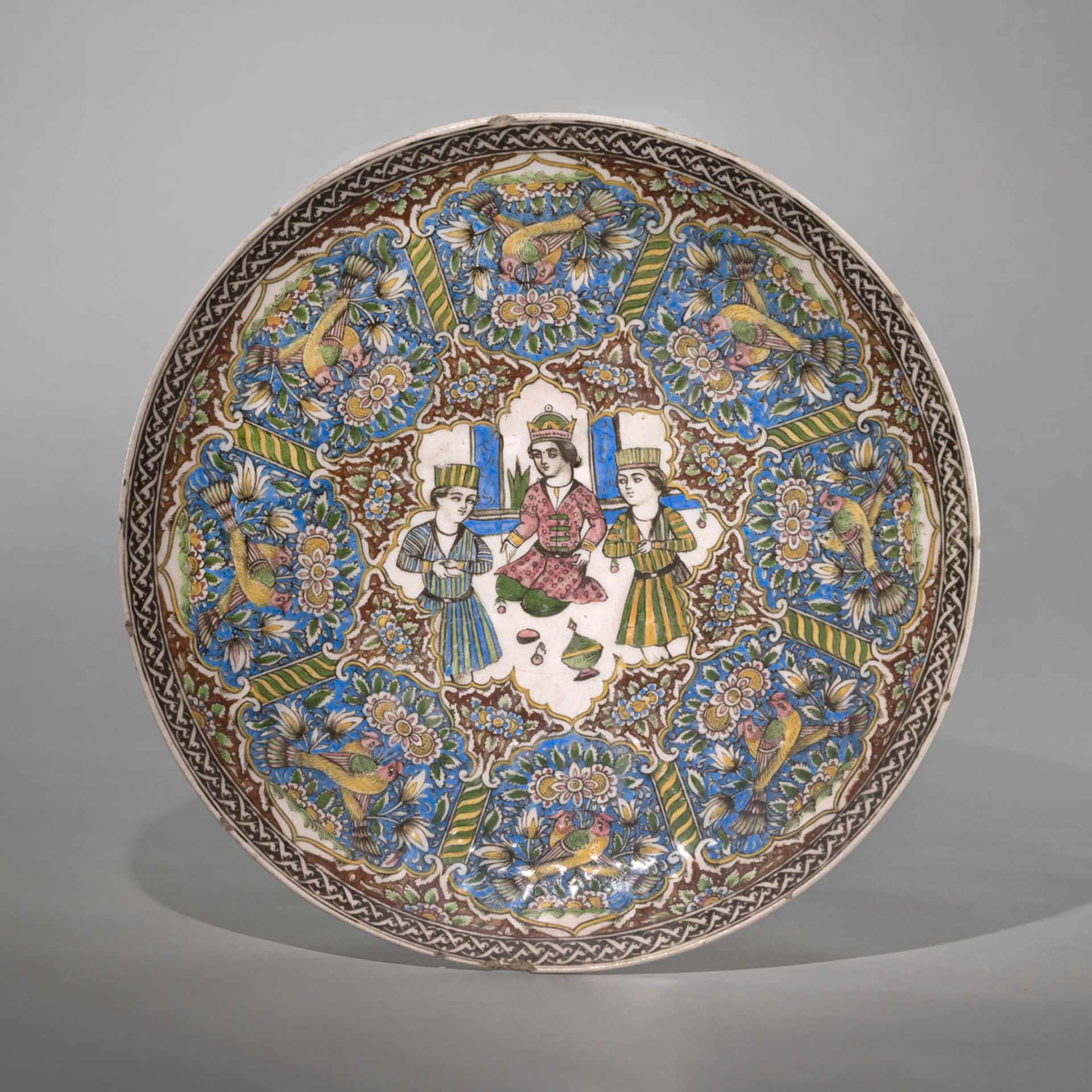 A QAJAR GLAZED POTTERY DISH WITH FINE DECORATION OF FIGURES, ANIMALS AND FLOWERS