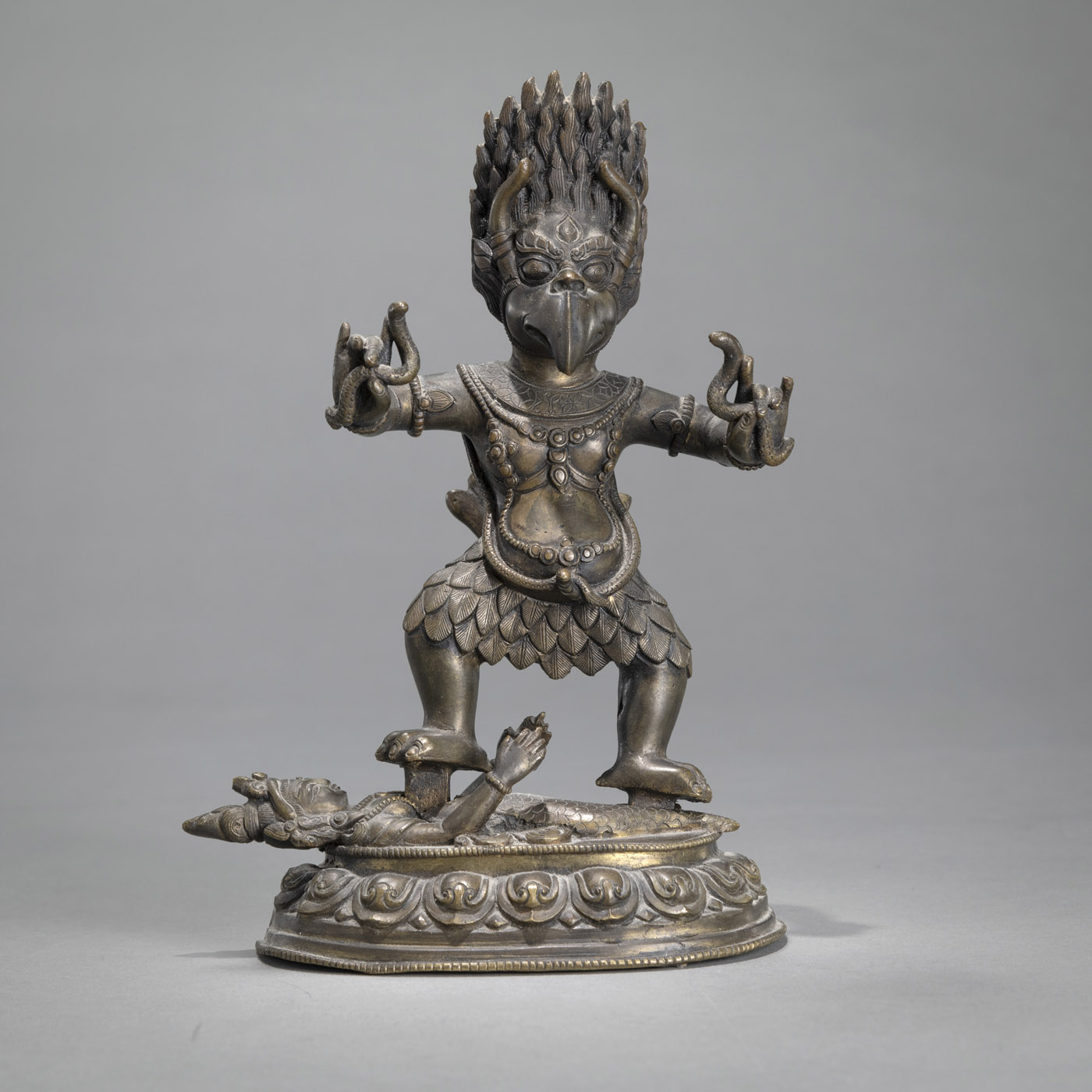 A BRONZE TANTRIC WRATHFUL GARUDA STANDING ON A FEMALE DRAGON FIGURE ON A BASE