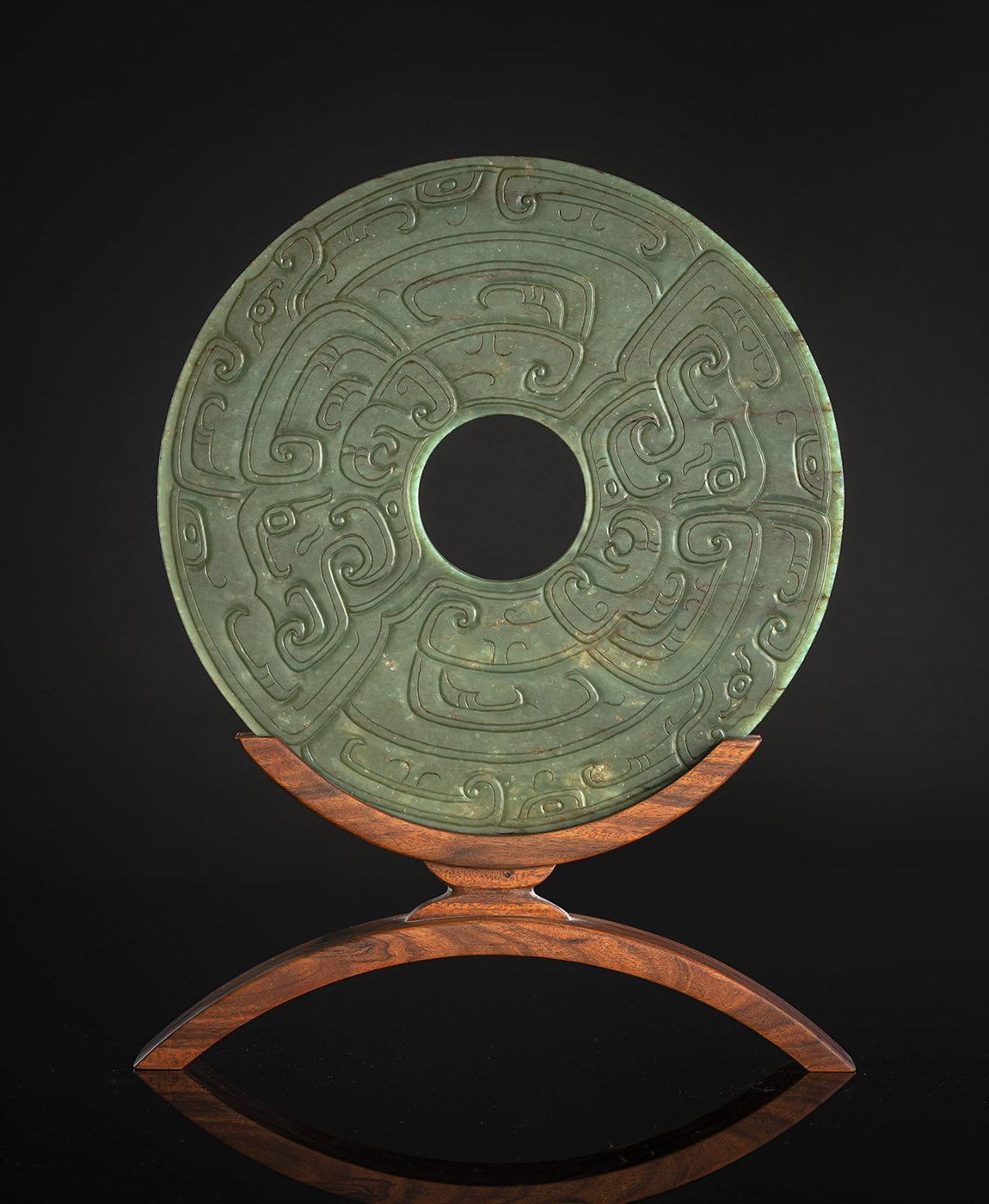 A FINE CARVED SPINACH GREEN JADE BI IN ARCHAIC STYLE ON WOOD STAND