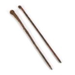 TWO BAMBOO/ROOTWOOD WALKING STICKS ONE WITH CARVED DECORATION OF ASHINAGA