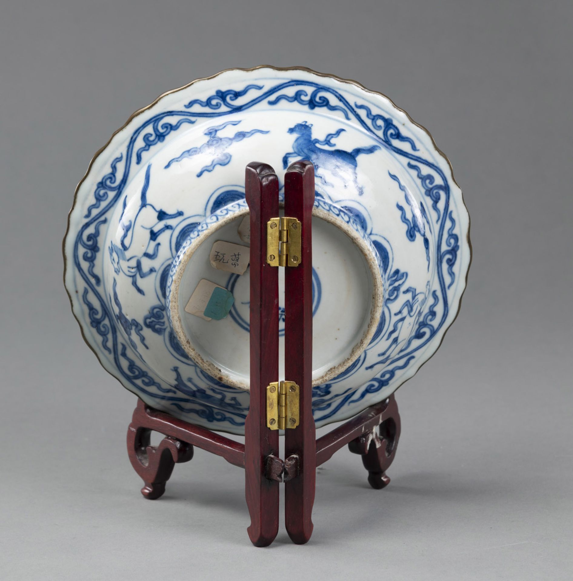 A BLUE AND WHITE FOLDED EDGE DISH DECORATED WITH LIONS, CRANES AND HORSES, WITH A WOODEN STAND - Image 3 of 3