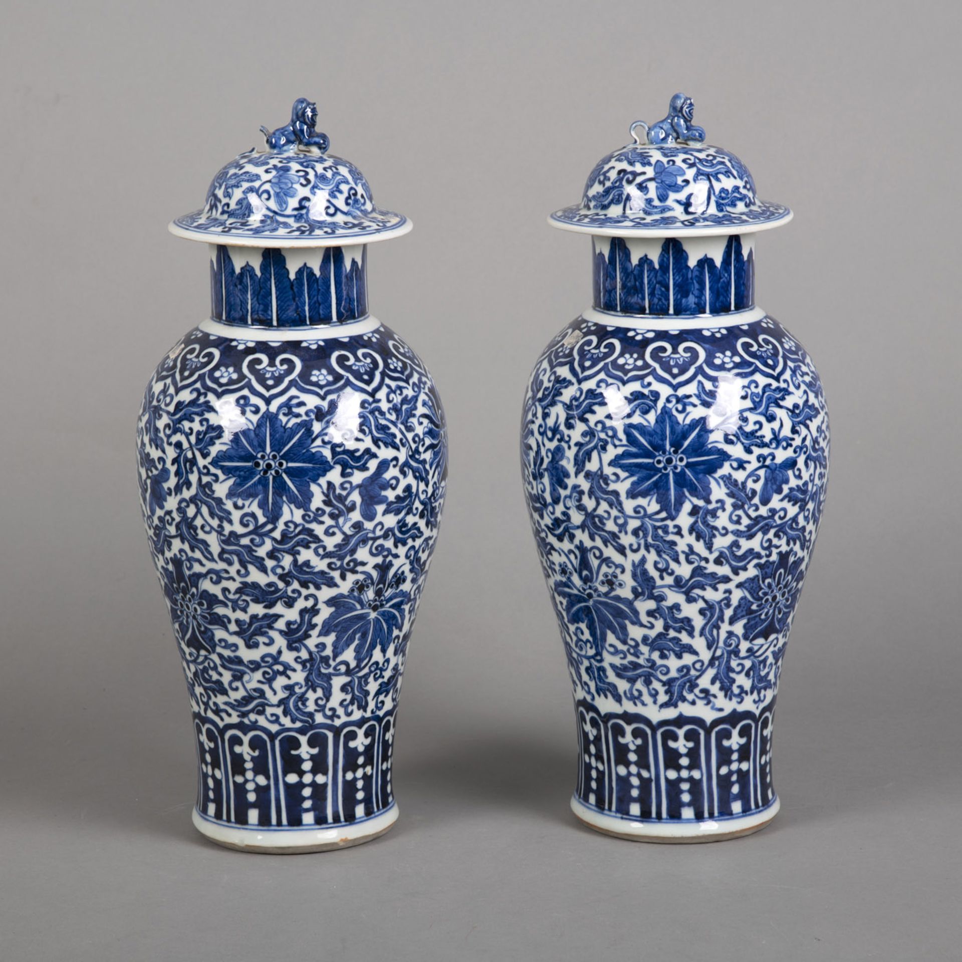 A PAIR OF BLUE AND WHITE PORCELAIN VASES WITH LION-HANDLED COVERS