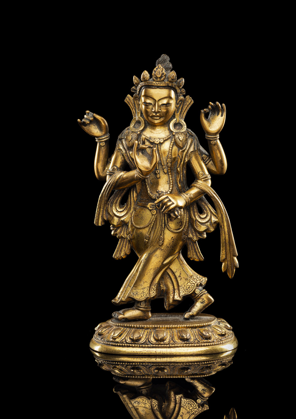 A RARE GILT-BRONZE OF A FOUR-ARMED FIGURE OF AN OFFERING GODDESS