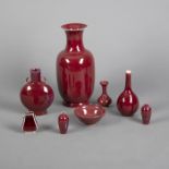 Konvolut rot-glasiertes Porzellan, teils lavendelblau gefleckt: sieben Vasen und eine Schale