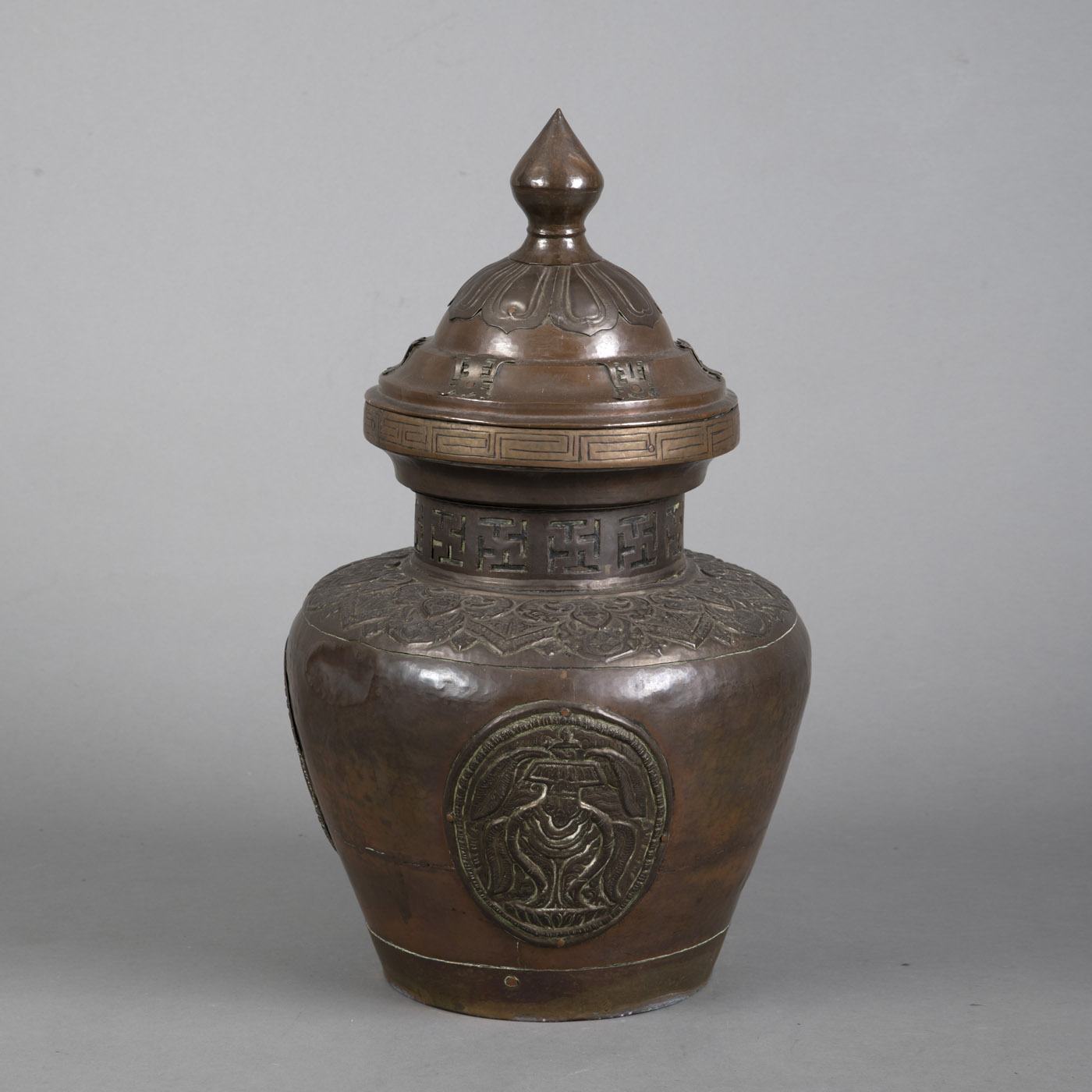 A LARGE EMBOSSED COPPER AND BRASS STORAGE VESSEL WITH SURROUNDING SWASTIKA AND "SHOU" CHARACTER DEC