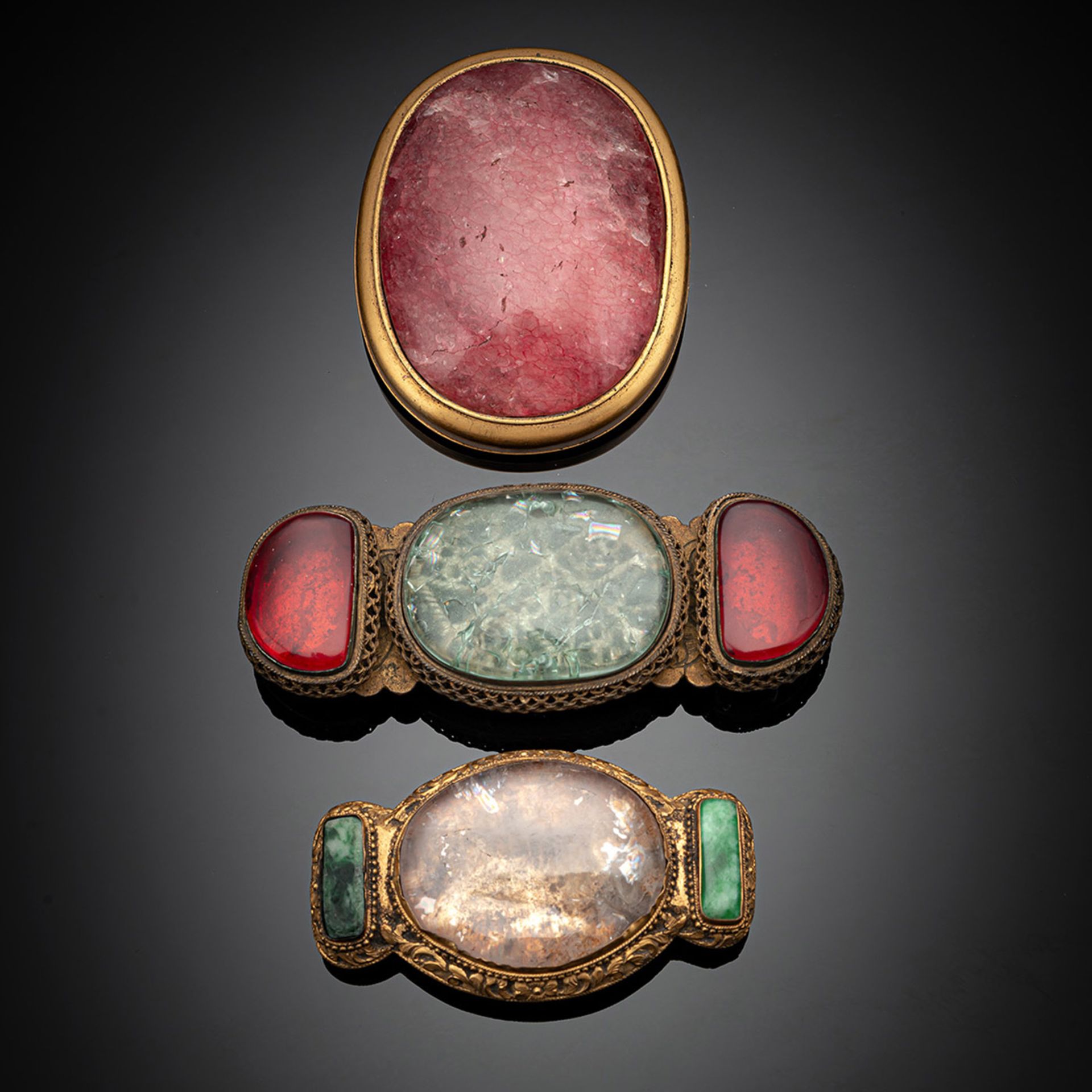 Drei Gürtelschließen aus feuervergoldeter Bronze mit Rosenquarz-, Kristall oder Jadeit-Einlagen