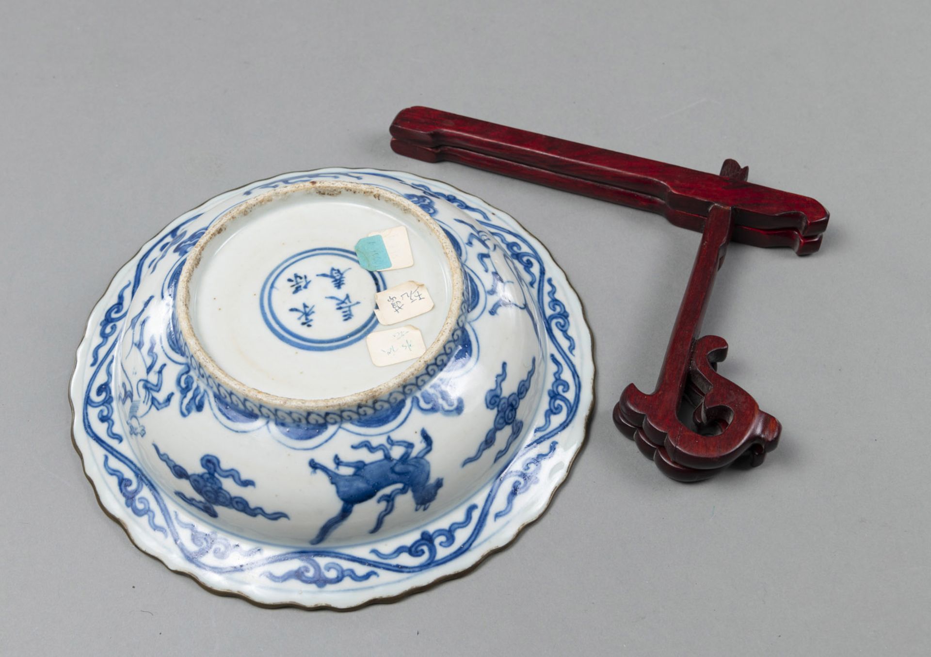 A BLUE AND WHITE FOLDED EDGE DISH DECORATED WITH LIONS, CRANES AND HORSES, WITH A WOODEN STAND - Image 2 of 3